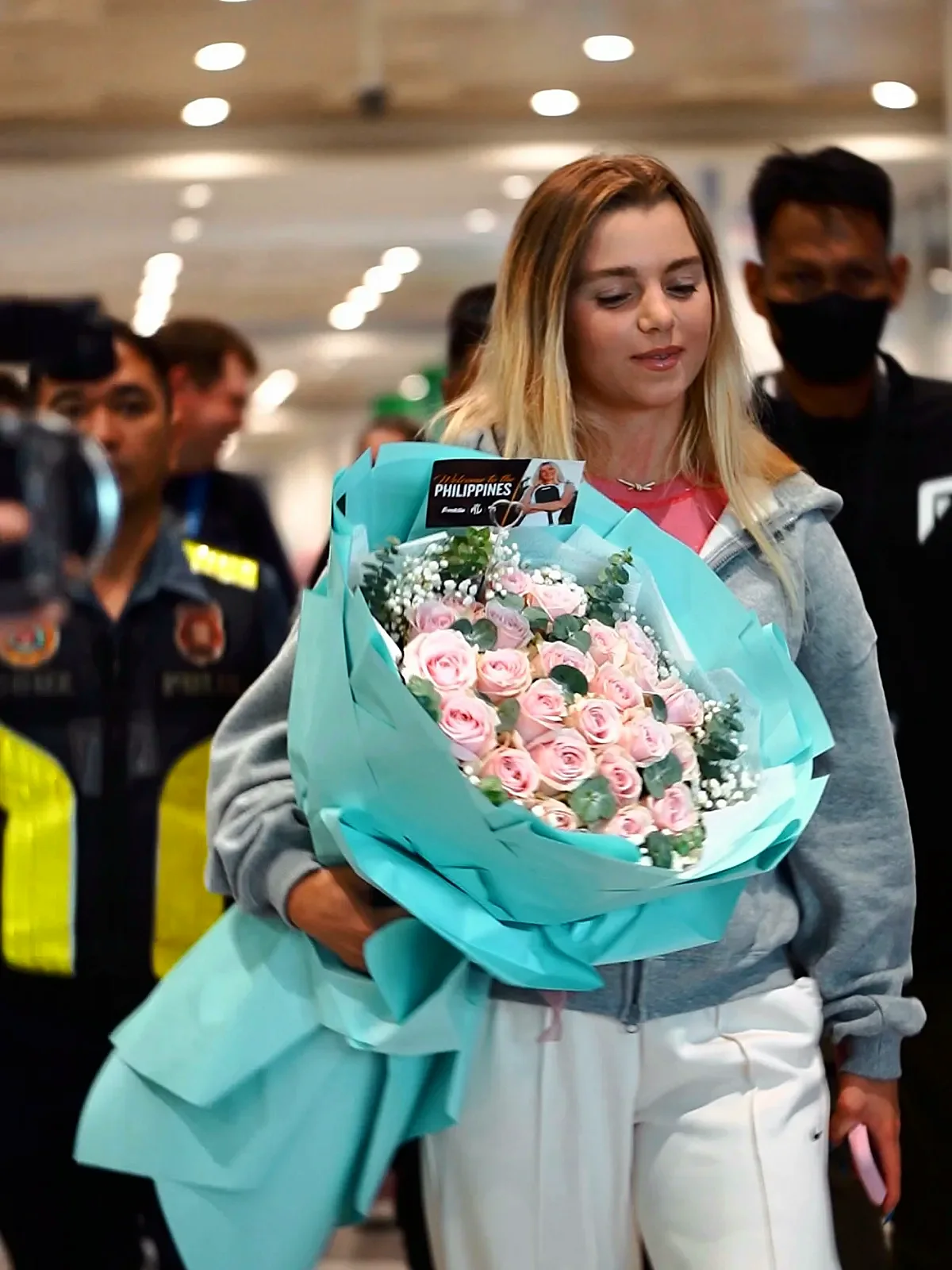 Anna Leigh Waters walks through NAIA arrivals holding roses