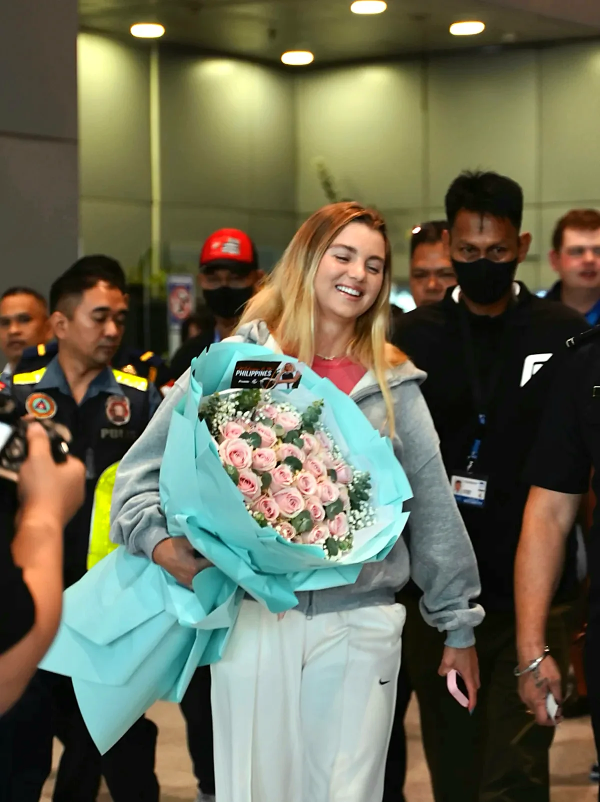 Anna Leigh Waters smiles at fans in NAIA arrivals