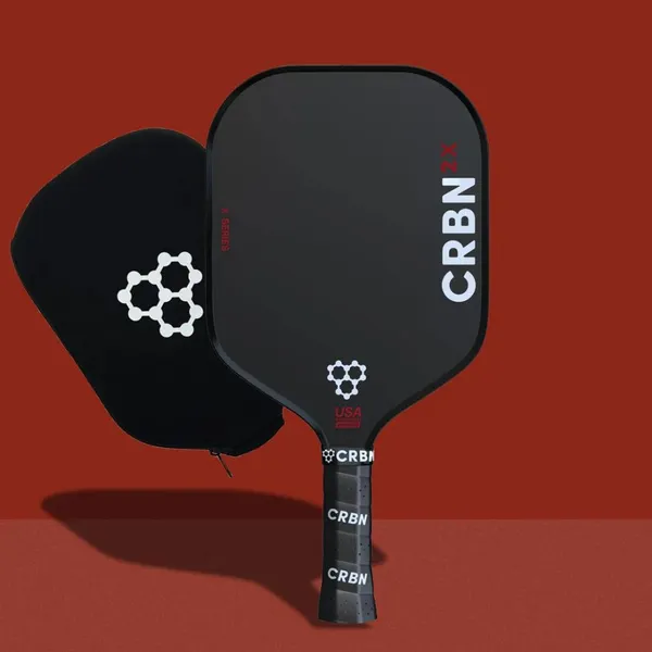 CRBN 2X Pickleball Paddle on red background with included paddle cover shown